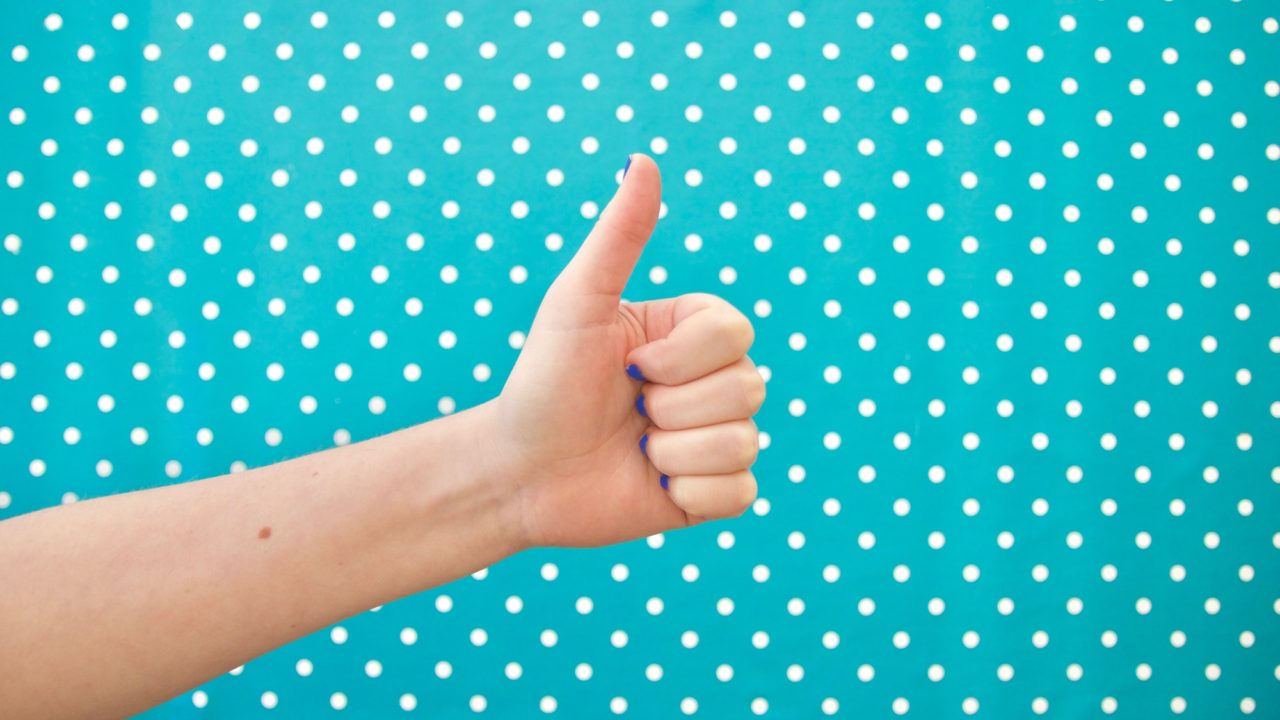 Thumbs up on bright polkadot background